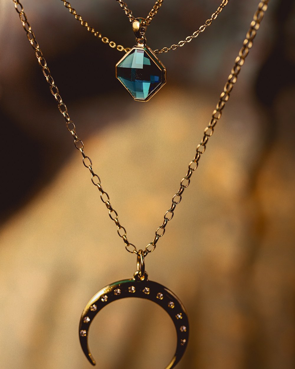 Photorealistic concept visual of an intricate gold-toned chain with gemstone pendant and crescent motif. Illustrative design reference only, not current shop stock.
